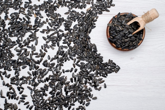 Free photo a top view black sunflower seeds fresh and tasty all over the white background grain sunflower seed granule