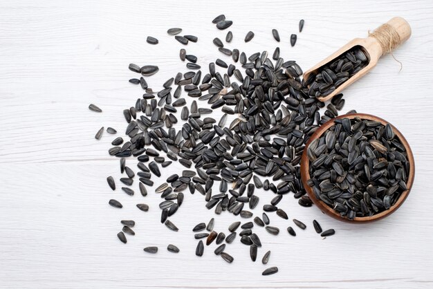 A top view black sunflower seeds fresh and tasty all over the white background grain sunflower seed granules