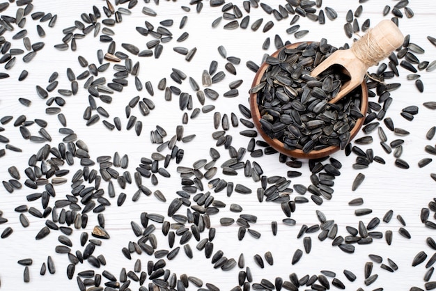 Вид сверху черные семена подсолнечника свежие и вкусные на белом фоне зерно подсолнечное масло закуски