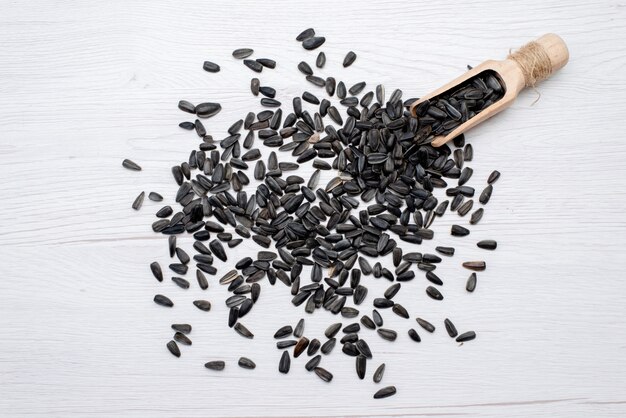 A top view black sunflower seeds fresh and tasty all over the white background sunflower seed snack oil
