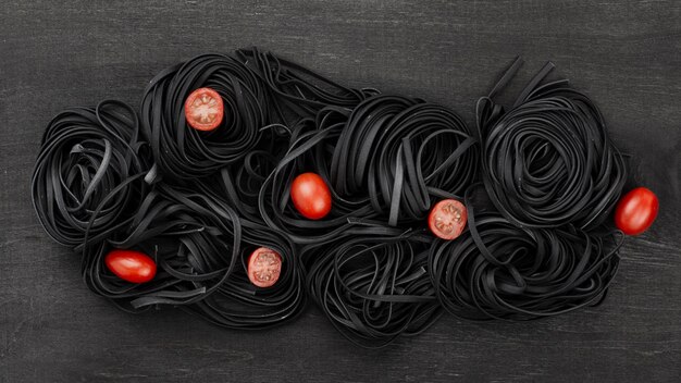 Top view of black tagliatelle with tomatoes