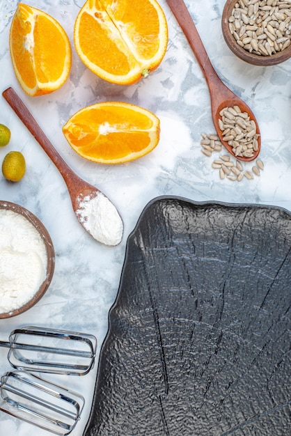 Free photo top view of black tray and flour brown rice in bowl fresh oranges on white background