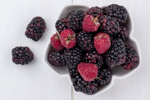 Free photo top view of blackberry with raspberries in a bowl on a white surface