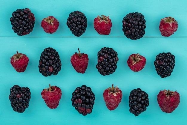 Top view of blackberry with raspberries on a light blue surface