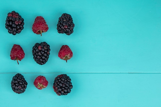 Top view of blackberry with raspberries on a light blue surface