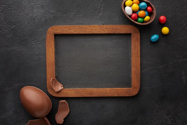 Top view of blackboard with chocolate easter eggs filled with colorful candy
