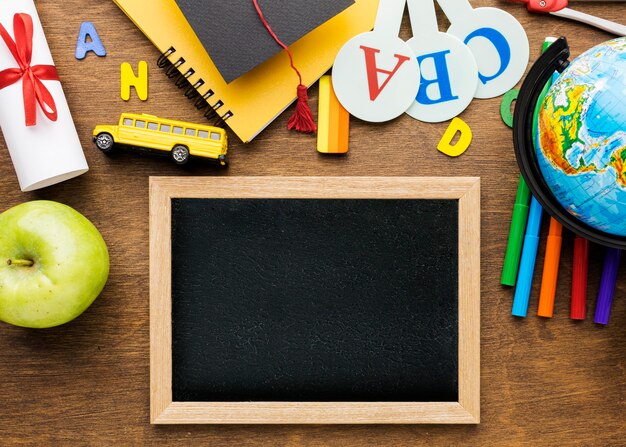 Top view of blackboard with school supplies and apple