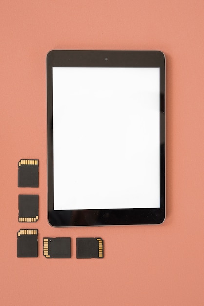 오렌지 배경 위에 메모리 카드와 함께 빈 디지털 태블릿의 상위 뷰