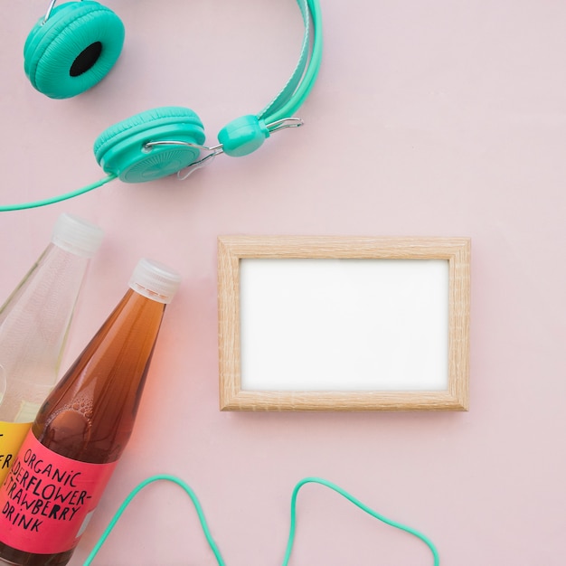 Free photo top view of blank frame, headphones and bottles