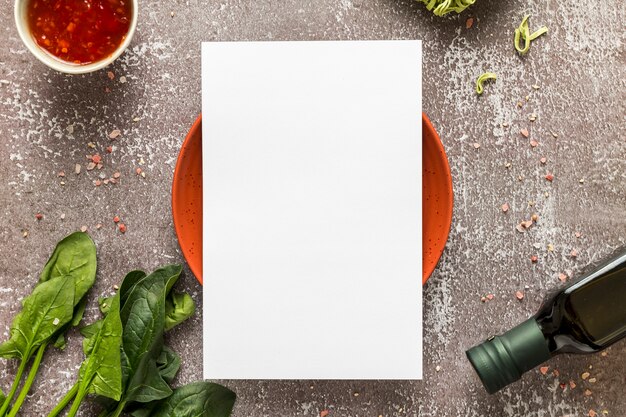 Вид сверху пустой меню бумаги на тарелку со шпинатом и оливковым маслом
