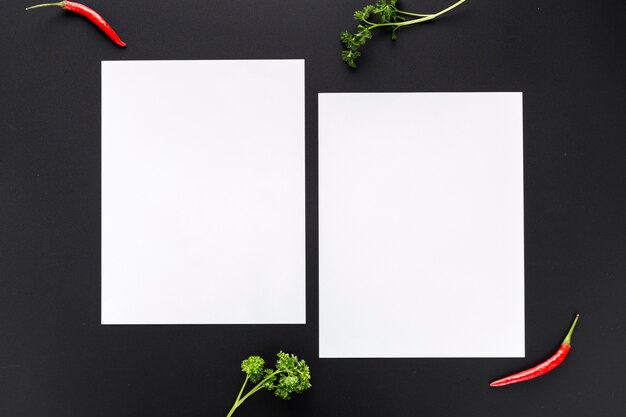 Top view of blank menu papers with peppers and greenery