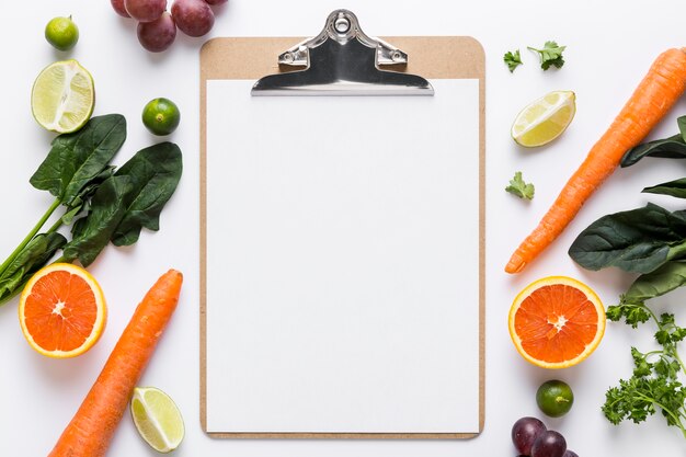 Top view of blank menu with spinach and carrots