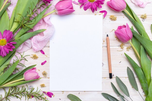 Top view of a blank paper and pencil decorated with purple flowers