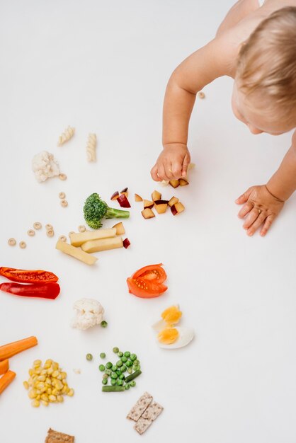 Top view blond baby choosing what to eat