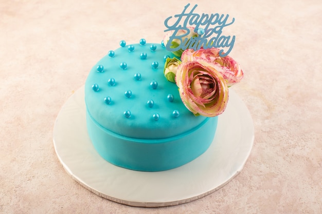 ピンクの机のお祝いパーティーの誕生日の上に花と上から見る青い誕生日ケーキ