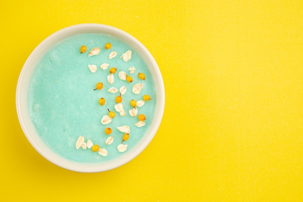 Foto gratuita dessert ghiacciato blu di vista superiore all'interno del piatto sul colore del cereale del latte della tabella gialla
