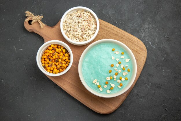 Top view blue iced dessert with raw muesli on dark table ice color cream