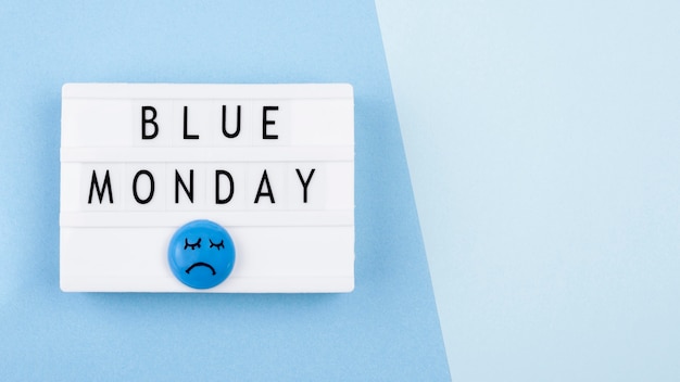 Top view of blue monday light box with sad face and copy space