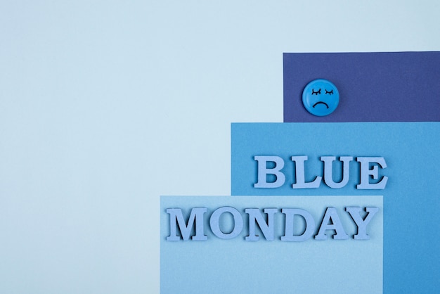 Top view of blue monday paper with sad face