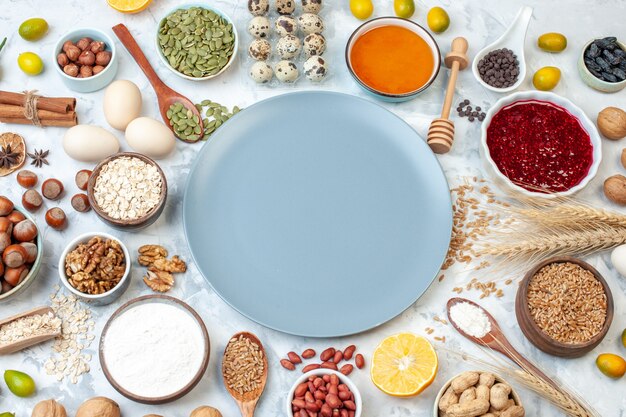 Вид сверху синяя тарелка с мучным желе, яйцами и разными орехами на белом тесте, фруктовый торт, сахар, фото, сладкий цвет, пирог