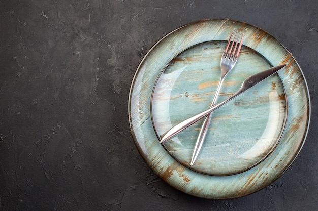 Free photo top view blue plate with fork and knife inside on dark surface