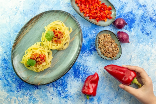 파란색 테이블에 맛있는 파스타와 필요한 야채 고기가 있는 파란색 접시의 상단