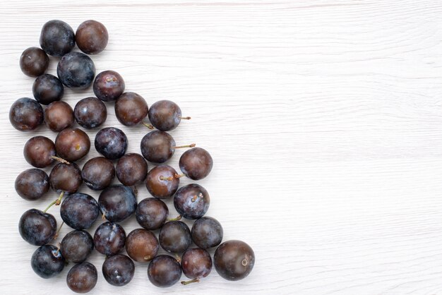 Вид сверху синие сливы круглые, сформированные на светлом фоне, фрукты, спелые, кислые, сочные