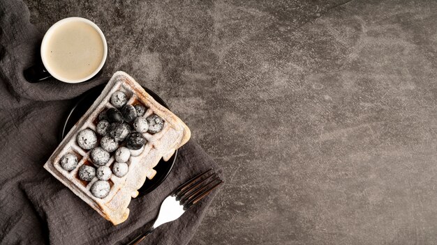 Top view of blueberries on waffles covered in powdered sugar