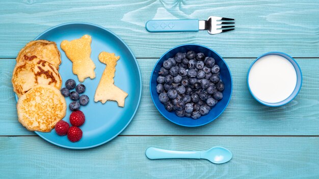 Top view of blueberries with baby food and cutlery