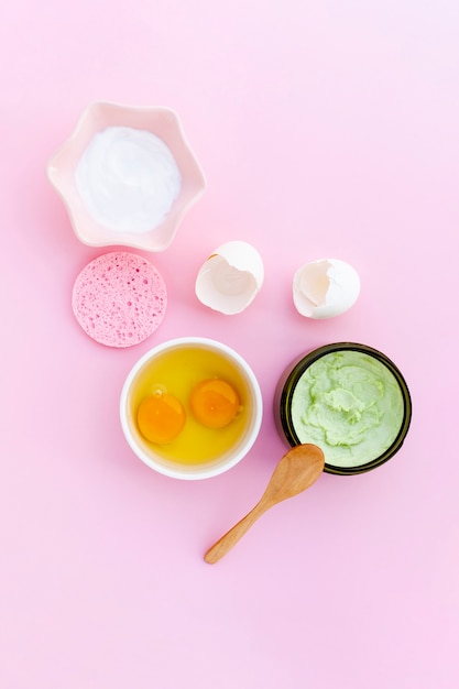 Top view of body butter and eggs on pink background