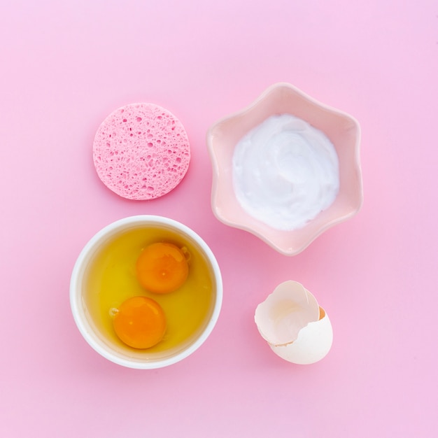 Foto gratuita vista dall'alto di burro per il corpo e uova su sfondo rosa