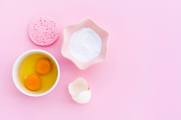 Top view of body butter and eggs on pink background