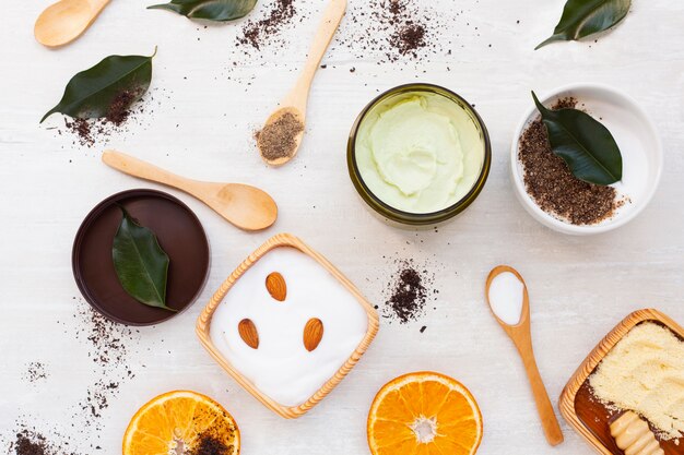 Top view of body butter and leaves on plain background