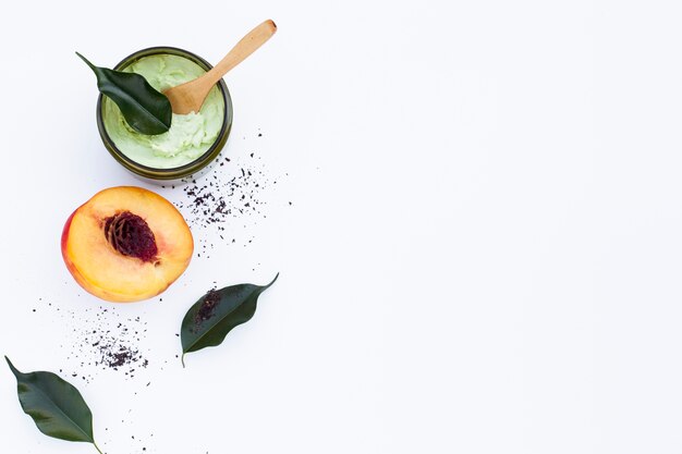 Top view of body butter and nectarine on plain background