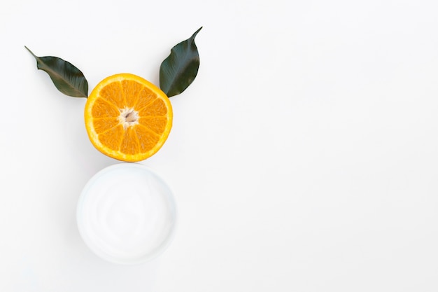 Top view of body butter and orange on white background