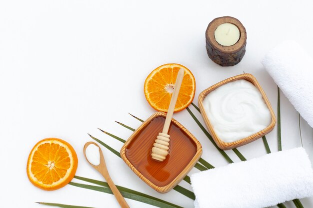 Top view of body butter and oranges on white background