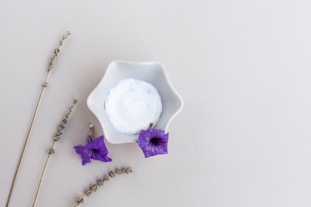 Top view of body cream and lavander on plain background