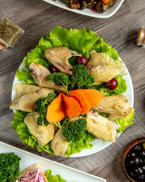 Top view boiled chicken with herbs on lettuce leaf with carrot slices