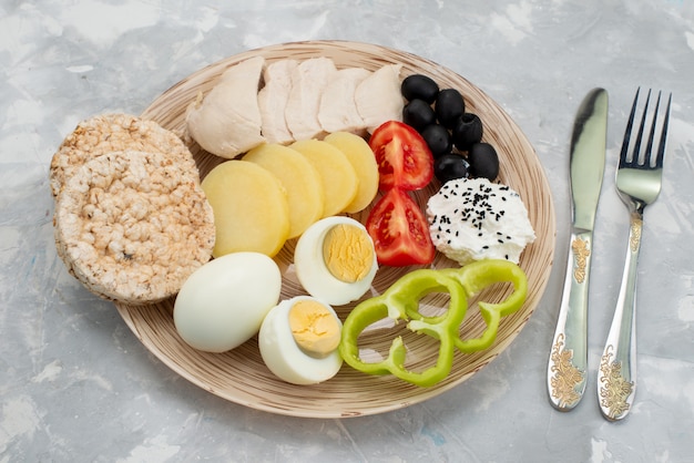 Top view boiled eggs with olives breasts seasonings crackers and tomatoes on grey, vegetable food meal breakfast