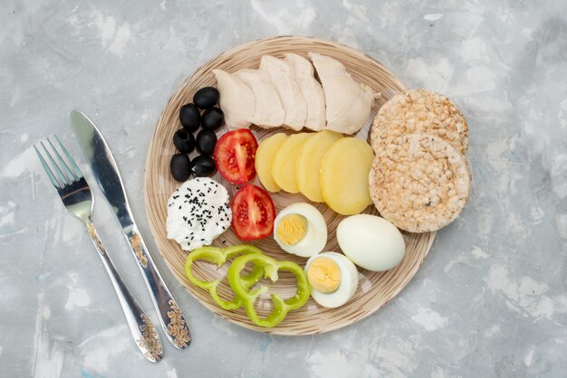 トップビューゆで卵とオリーブの胸肉の調味料とトマトの灰色、野菜料理の食事の朝食