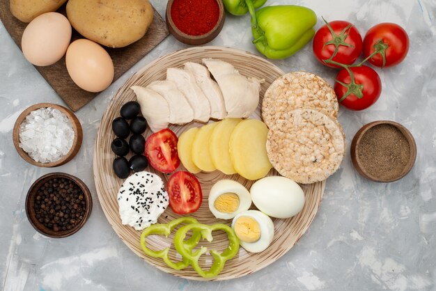 Top view boiled eggs with olives pepper breasts and tomatoes on grey, vegetable food meal breakfast