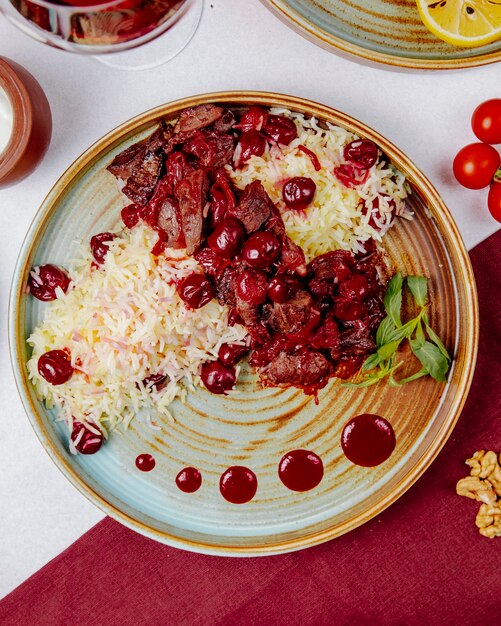 Top view of boiled rice with meat and cherries
