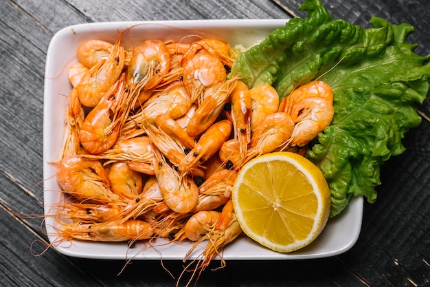 Top view boiled river shrimps on a leaf of lettuce with lemon