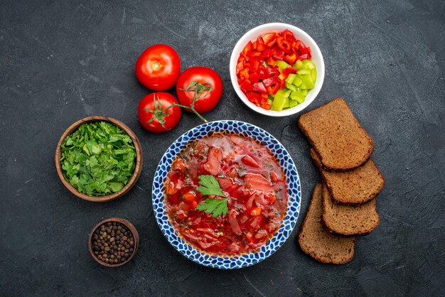 Top view borsch soup with dark bread loafs and greens on dark space