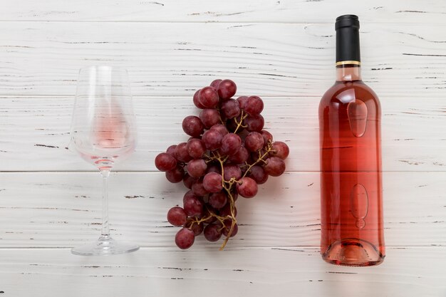 Top view bottle of wine with glass and bunch of grapes