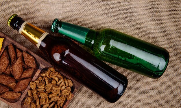 Top view of  bottles of bee with bread crackers on sackcloth texture