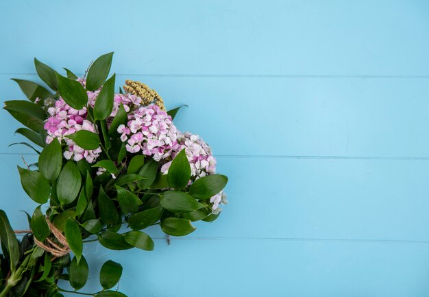 Free photo top view of bouquet of light purple flowers with leaf branches on a light blue surface