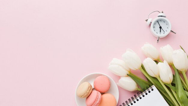 Top view bouquet of tulip flowers with sweets and clock