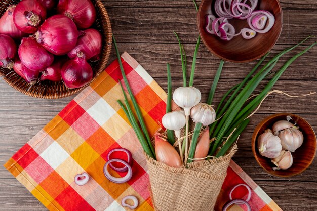 Top view of bouquet of vegetables as green onion garlic shallot on plaid cloth on wooden background