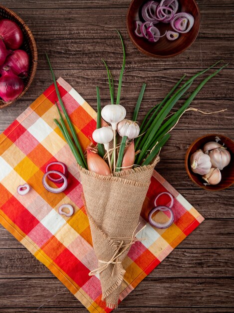 Top view of bouquet of vegetables as onion shallot and garlic on cloth on wooden background